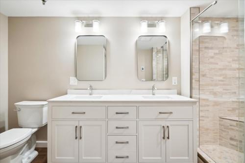 a bathroom with a sink and a toilet and two mirrors at Highridge A16 Stunning Three Bedroom Condo with Whirlpool Bath, Heated Pool, and Game Room in Killington