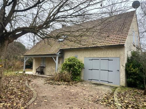 une porte de garage blanche sur une maison blanche dans l'établissement L'agréable Maison de Noisy, calme, T5, à Noisy-sur-École