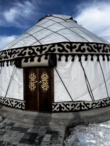 a yurt with a wooden door in the snow at Ethnochill Karakol yurt camping in Karakol