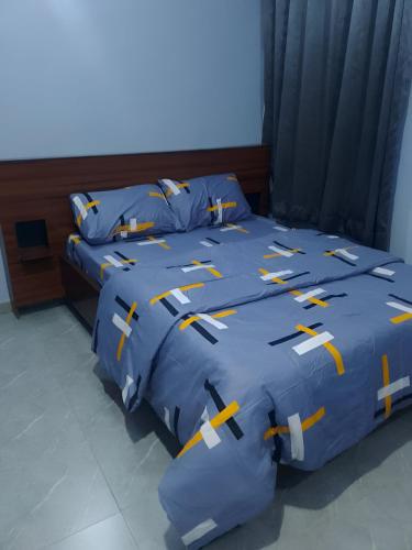 2 camas con edredones azules y almohadas amarillas y blancas en Becktab - Comfort Apartments Surulere, en Suru Lere