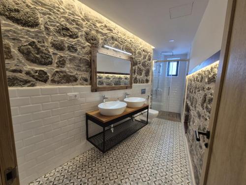 a bathroom with two sinks and a stone wall at Casa Federico & Manuela – Piscina Climatizada in Mogán