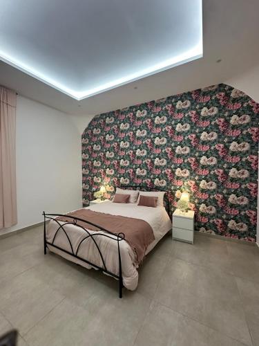 a bedroom with a large bed with a floral wall at Le FATE DI V E N E R E in Caserta