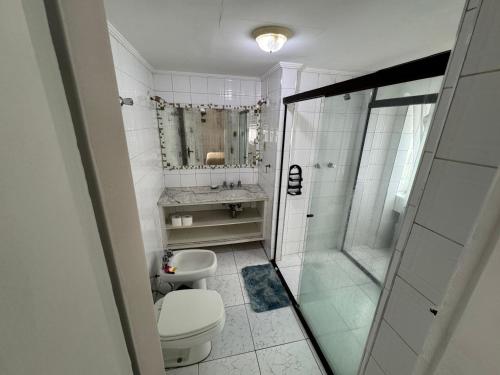 a white bathroom with a toilet and a shower at Apartamento em frente ao mar in Guarujá