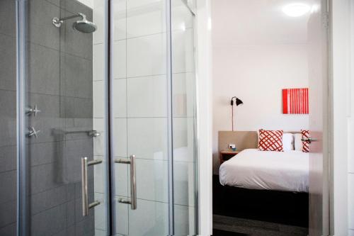 a bathroom with a glass shower with a bed at Villawood Hotel in Villawood