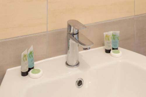 a sink with a faucet and three toothbrushes at Stylish 1 Bed Apartment in Town Centre in Berwick-Upon-Tweed