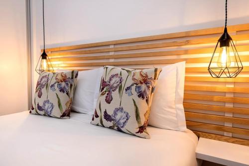 a bed with two pillows and a wooden headboard at New Apartment by the Metro - 1E in Lisbon