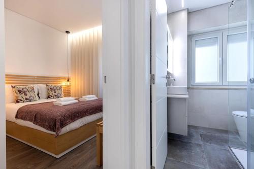 a bedroom with a bed and a bathroom with a sink at New Apartment by the Metro - 1E in Lisbon