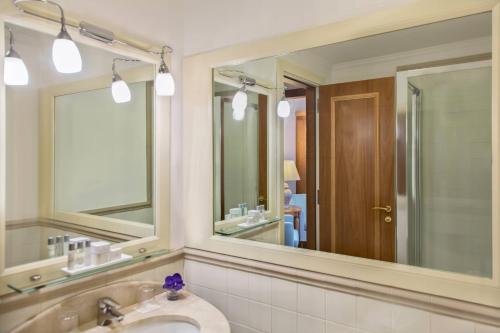 a bathroom with two mirrors and a sink at Renaissance Naples Hotel Mediterraneo in Naples