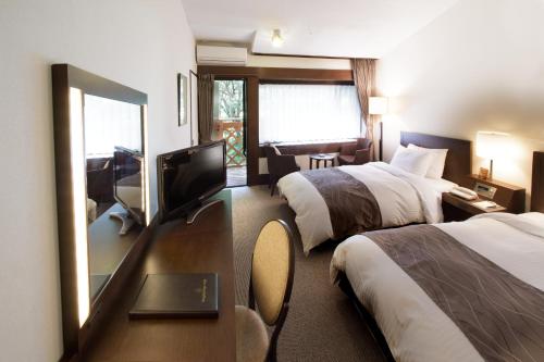 a hotel room with two beds and a flat screen tv at Yatsugatake Kogen Lodge in Minamimaki