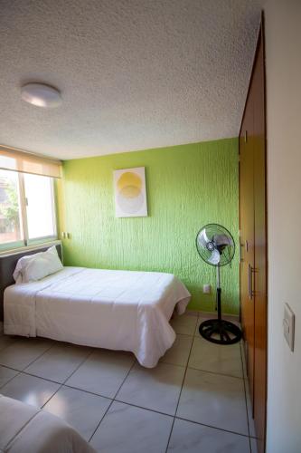 a bedroom with a white bed and a green wall at Bonitos departamentos frente a la Expo Guadalajara in Guadalajara