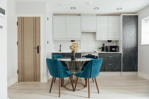 a kitchen with a table and blue chairs at Modern 2Bed House - Walk to Station & High Street, Near Surrey Hills & Denbies Vineyard in Dorking
