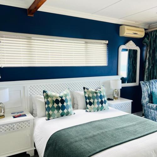 a bedroom with blue walls and a white bed with pillows at Blue View B&B in East London