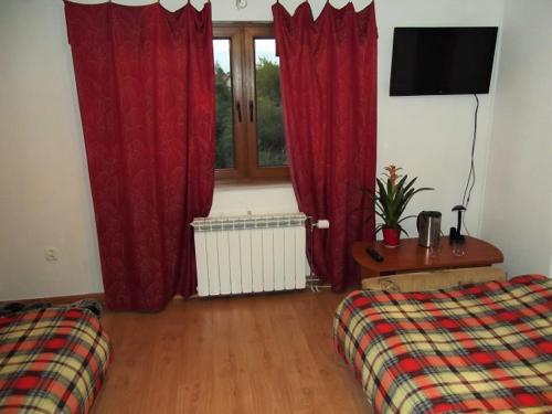 a room with two beds and a window with red curtains at Dworek w Zieleni in Warsaw