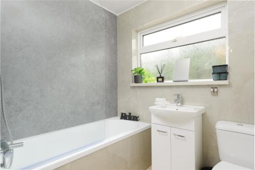 a bathroom with a white tub and a sink and a window at Bright & Stylish Home Nestled at the Edge of Exmoor in Tiverton