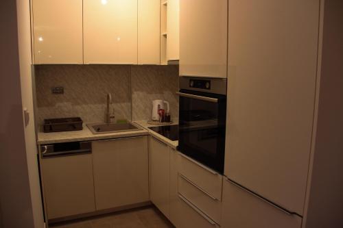 a kitchen with white cabinets and a sink and a stove at Apartman Doboj in Doboj