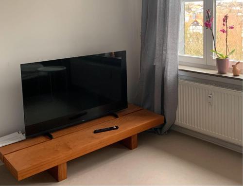 a flat screen tv sitting on a wooden stand next to a window at Modern wohnen im Fachwerkhaus im Herzen Wolfhagens - 2 Schlafzimmer, Parkplatz in Wolfhagen