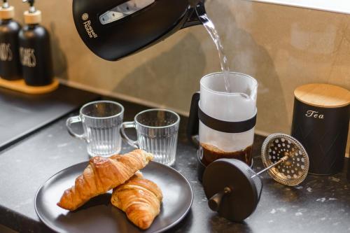 a plate of croissants on a counter with a coffee maker at Bright & Stylish Home Nestled at the Edge of Exmoor in Tiverton