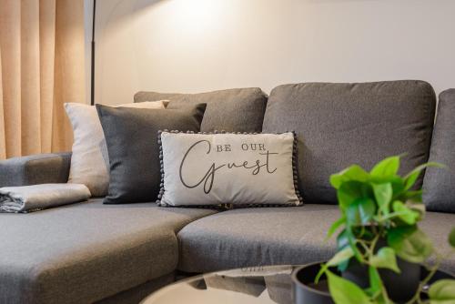 a gray couch with a pillow that says be our guest at Bright & Stylish Home Nestled at the Edge of Exmoor in Tiverton