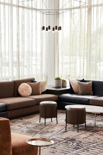 a living room with a couch and tables and windows at AC Hotel by Marriott Nashville Brentwood in Brentwood