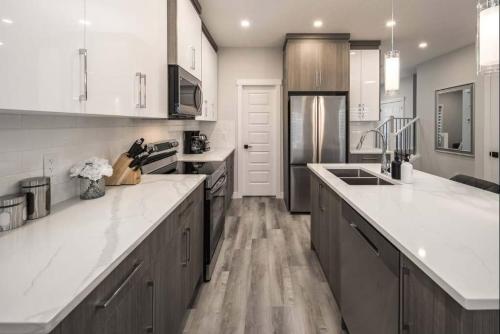 a large kitchen with white counter tops and wooden cabinets at NEW Family 3BR w Yard, Sleeps 8! FREE Banff Pass, Wine, Netflix, Parking! Large Group OPTION! in Calgary
