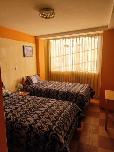 a hotel room with two beds and a window at Hostal Vista al Lago Titicaca Puno in Puno