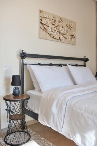 a bedroom with a bed with white sheets and a table at ATHENS VILLA KROPIA #AthensAirport #AirView #Sunrise in Koropíon