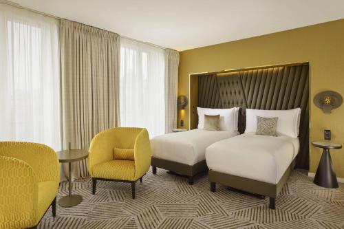 a hotel room with two beds and a chair at La Caserne Chanzy Hotel & Spa, Autograph Collection in Reims