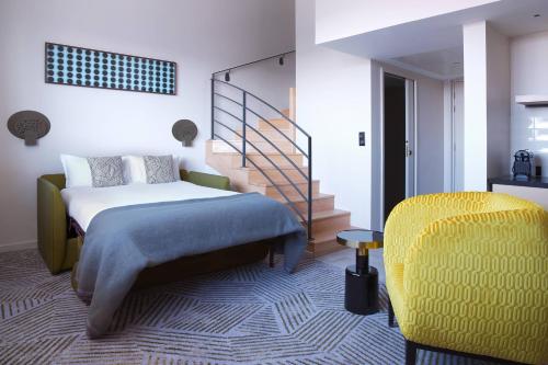 a bedroom with a bed and a yellow chair at La Caserne Chanzy Hotel & Spa, Autograph Collection in Reims