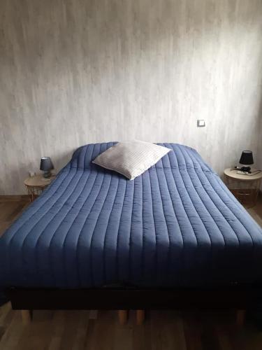 - un lit avec une couette bleue et 2 tables dans l'établissement les coquelicots en baie de Somme, à Saint-Blimont