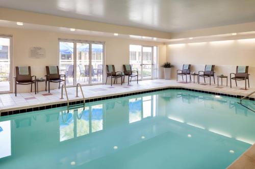 a swimming pool with chairs and tables in a building at Fairfield Inn by Marriott Loveland Fort Collins in Loveland