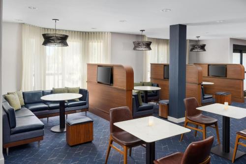 a waiting room with tables and chairs and a tv at Courtyard By Marriott Salinas Monterey in Salinas