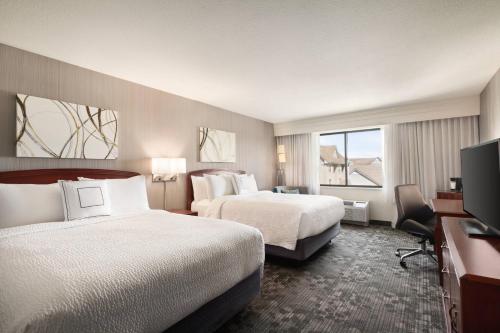 a hotel room with two beds and a flat screen tv at Courtyard By Marriott Salinas Monterey in Salinas