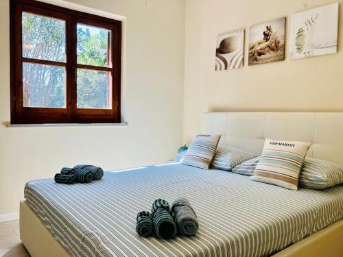 a bed in a white room with some pillows on it at Villetta con piscina e ampio giardino in Stintino