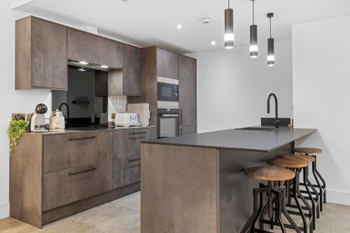 a kitchen with wooden cabinets and a island with bar stools at Luxury 2-Bed Apartment with Parking & Terrace in Nottingham