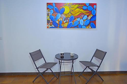 a table with three chairs and a painting on the wall at Caracol Magico in Rometta Marea