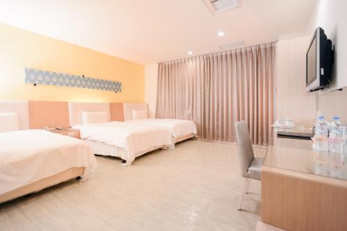 a hotel room with two beds and a flat screen tv at i-Deal Hotel in Taichung