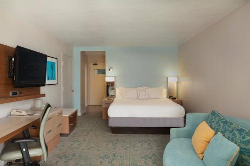 a hotel room with a bed and a couch and a desk at Courtyard by Marriott Isla Verde Beach Resort in San Juan