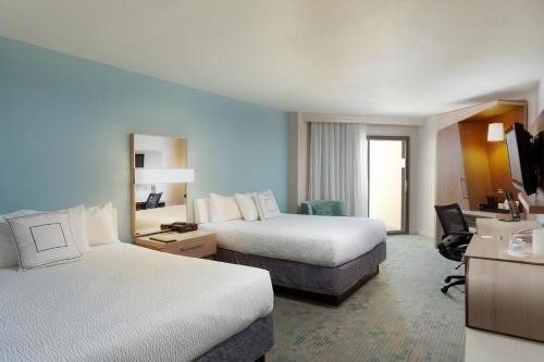 a hotel room with two beds and a desk at Courtyard by Marriott Isla Verde Beach Resort in San Juan