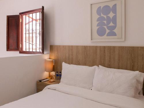 a bedroom with a bed with a wooden headboard and a window at Hotel Casa Agustina in Cartagena de Indias