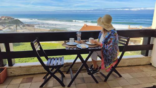 a woman sitting at a table with a cup of coffee at Santa Cruz Ocean Apartment - I in Santa Cruz