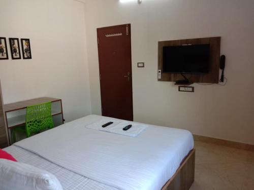 een slaapkamer met een bed en een flatscreen-tv bij Sk Residency in Bangalore