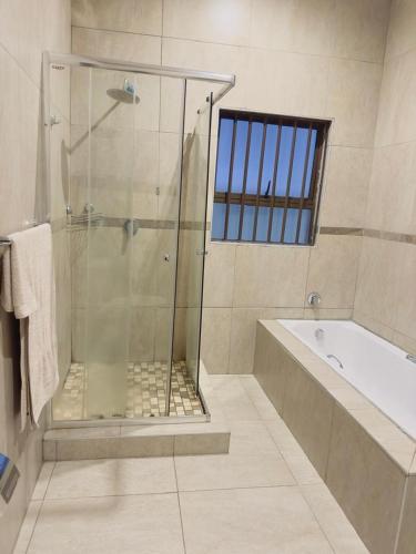 a bathroom with a shower and a tub and a sink at Elegant guest house in Matsapha