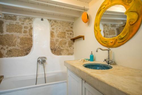 une salle de bain avec un lavabo, une baignoire et un miroir dans l'établissement Mandarin Greek Traditional Home, à Rhodes