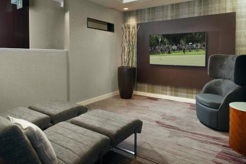 a waiting room with a tv and a couch and chairs at Courtyard by Marriott Raleigh Cary in Cary