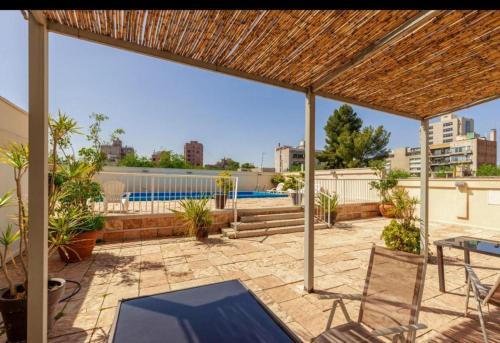 eine Terrasse mit Tisch und Stühlen und einem Pool in der Unterkunft MZA Departamentos in Mendoza