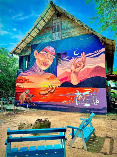 a mural on the side of a building with a bench at Playa del Ritmo Beach Hostel & Bar in Santa Marta