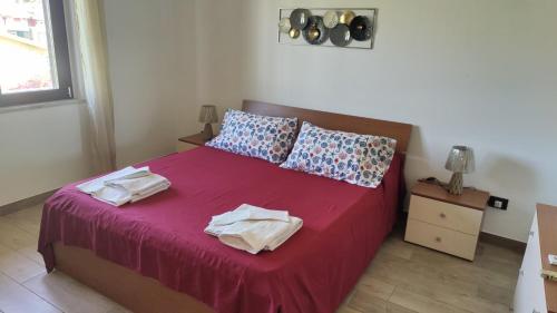 a bedroom with a red bed with towels on it at Casa Vacanza Casarcobaleno in Ardore Marina