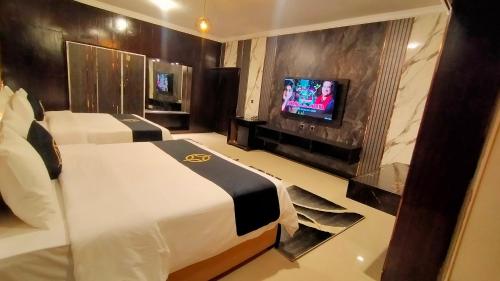 a hotel room with two beds and a flat screen tv at Hotel Oasis in Islamabad