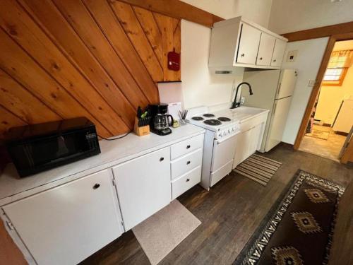 a kitchen with white cabinets and a stove and refrigerator at Chinook Winds Lodge in Dubois