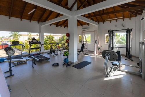 a gym with several treadmills and machines in a room at Bragha Apartments And Hotel in Takoradi